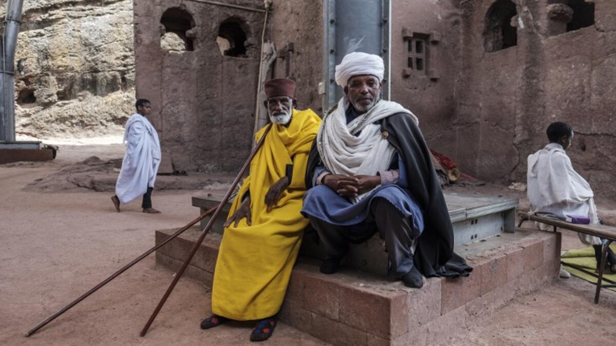 An Ethiopian Orthodox priest Mekonnen Fatne (R) poses near the church of Saint Mary which is covered by a shelter to protect its rock-hewn structure from erosion in Lalibela
EDUARDO SOTERAS / AFP