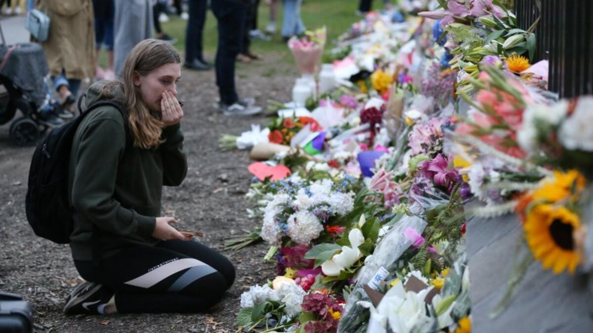 People pay their respects in front of floral tributes for victims of the March 15 mosque attacks, in Christchurch 
DAVID MOIR / AFP