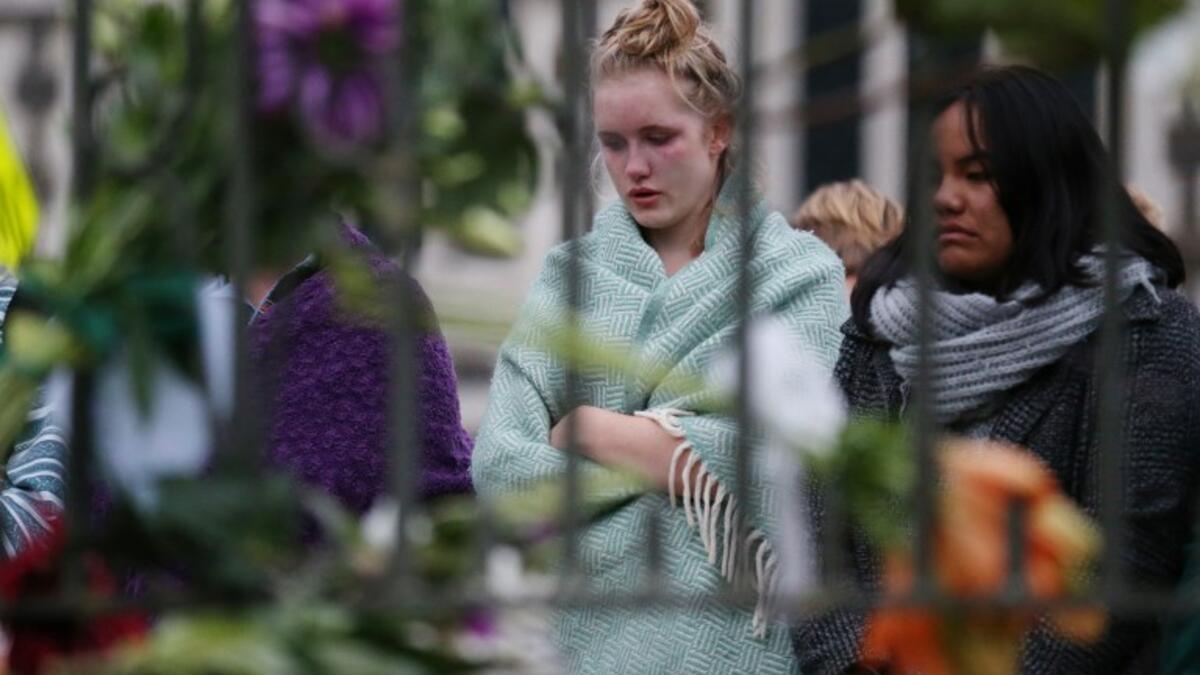 People pay their respects in front of floral tributes for victims of the March 15 mosque attacks, in Christchurch 
DAVID MOIR / AFP