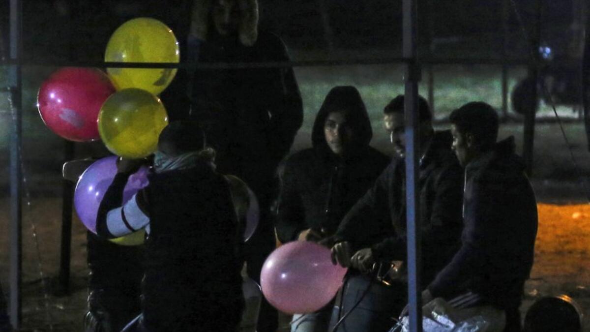 Palestinian protesters hold incendiary ballons that will be released over Israel, during a night demonstration near the fence along the border with Israel, in Rafah 
SAID KHATIB / AFP