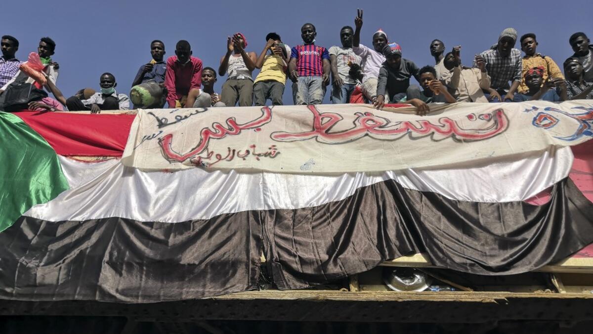 Sudanese men gather atop a pedestrian crossing with a national flag and a banner reading in Arabic "Just fall that is all", during a demonstration in front of the military headquarters in the capital Khartoum on April 9, 2019.
AFP/ File