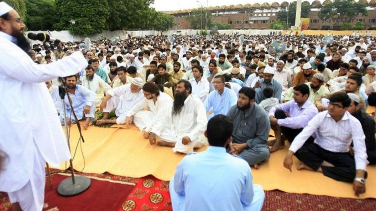 A congregation listens as Hafiz Mohammad Saeed (L), chief of Pakistan's outlawed Islamic hardline Jamaat ud Dawa (JD), delivers his sermon following congregational Eid al-Fitr prayers in Lahore on August 9, 2013. Saeed was the mastermind behind the 2008 terror attacks in Mumbai. (AFP)