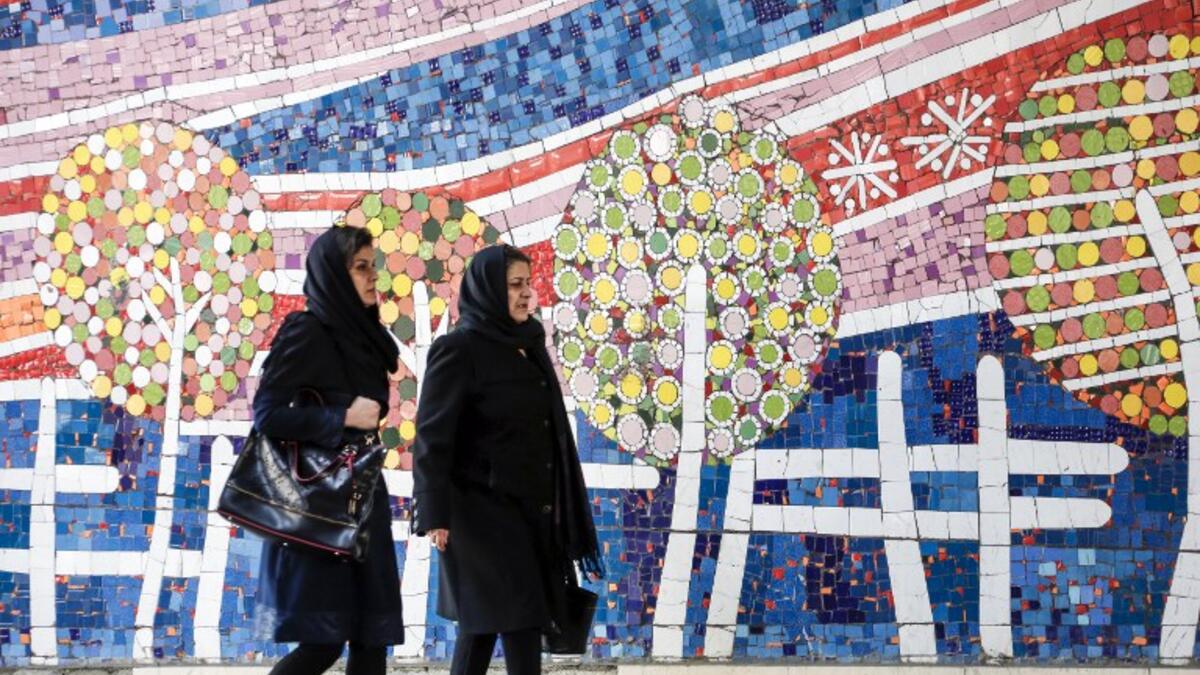 To women walks along a street past a mosaic mural on the first anniversary of the nuclear agreement in Tehran (Twitter)