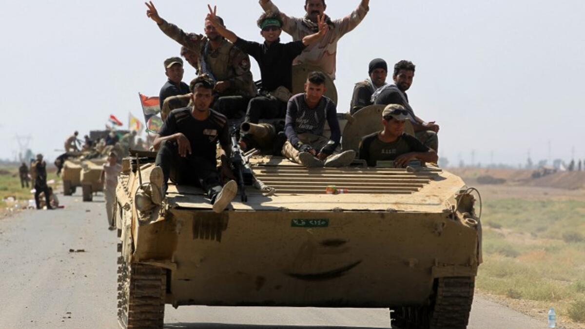 Members of the Hashed al-Shaabi (Popular Mobilization) paramilitaries flash the victory gesture as they ride atop an infantry-fighting vehicle during the advance towards villages between the northern Iraqi cities of Hawija and Kirkuk on October 6, 2017
AHMAD AL-RUBAYE / AFP