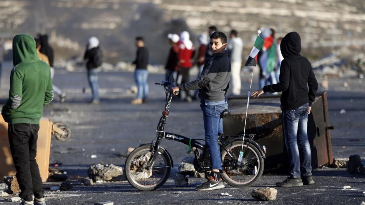A Palestinian boy rides his bike during clashes with Israeli forces near an Israeli checkpoint in the West Bank city of Ramallah.
(ABBAS MOMANI / AFP)