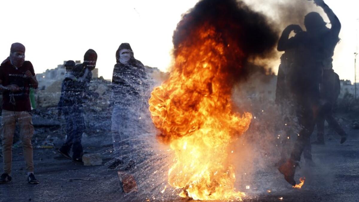 A Palestinian demonstrator kicks a burning tire during clashes with Israeli forces near an Israeli checkpoint in the West Bank city of Ramallah following the U.S. president's controversial recognition of Jerusalem as Israel's capital. 
(ABBAS MOMANI / AFP)