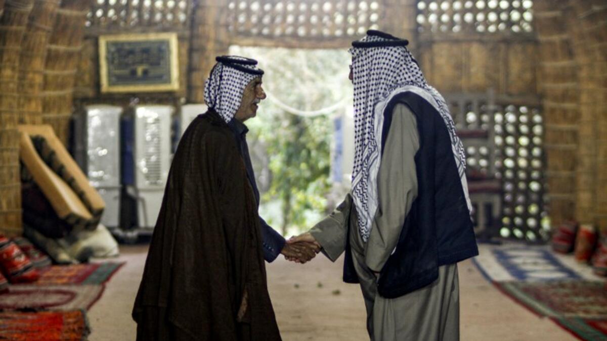 Members of an Iraqi clan shake hands as they meet inside a straw tent in the town of Mishkhab, south of Najaf on November 15, 2018. 
Haidar HAMDANI / AFP