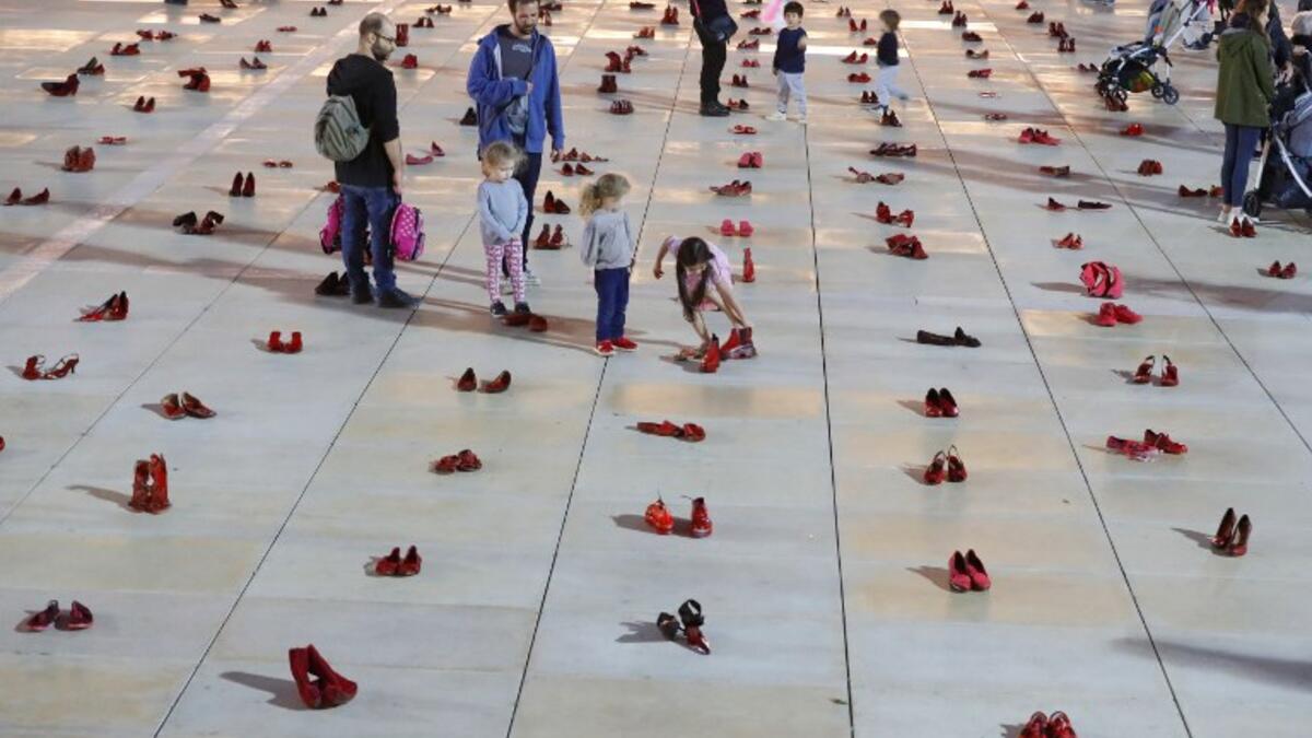 Israelis walk past an installation of red shoes during a rally against domestic violence in the Israeli coastal city of Tel Aviv on December 4, 2018. JACK GUEZ / AFP
