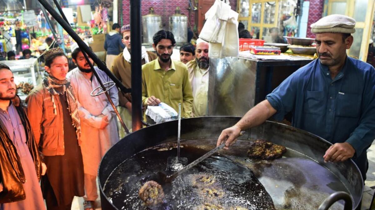 Pakistani cook grills kebabs while customers look on at the Tory Kebab House in Namak Mandi in Peshawar.
ABDUL MAJEED / AFP