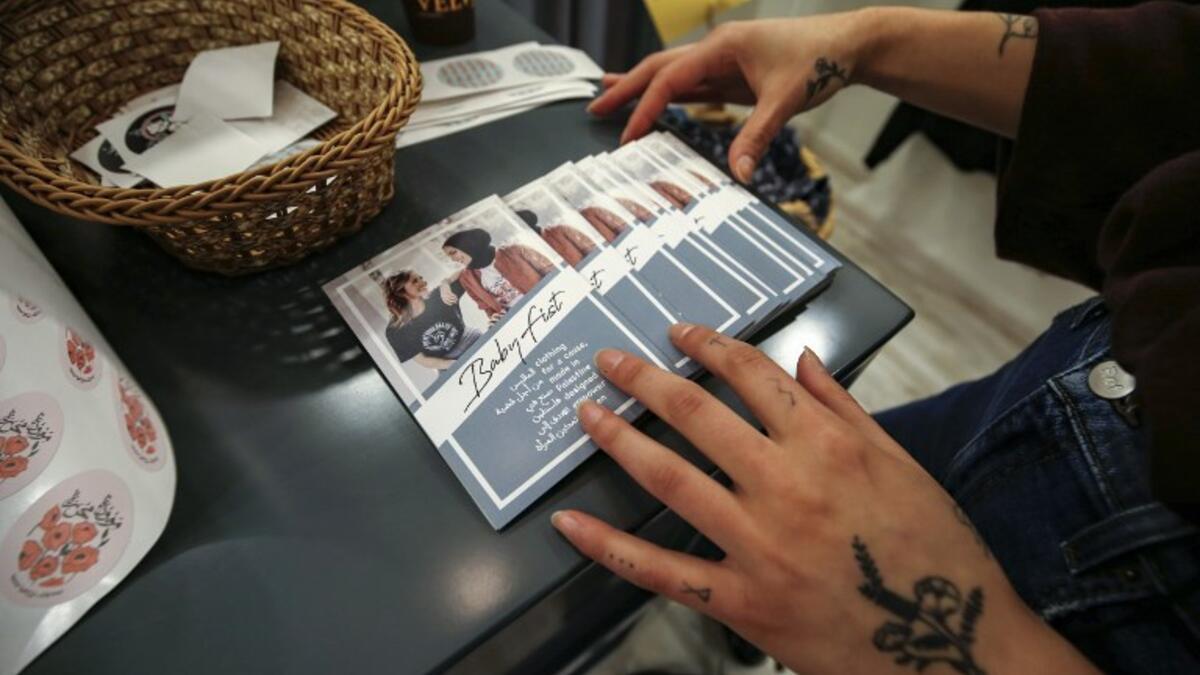 Palestinian fashion designer Yasmeen Mjalli arranges leaflets for her label collection "BabyFist" carrying anti-sexual harassment slogans in her shop in Ramallah 
ABBAS MOMANI / AFP