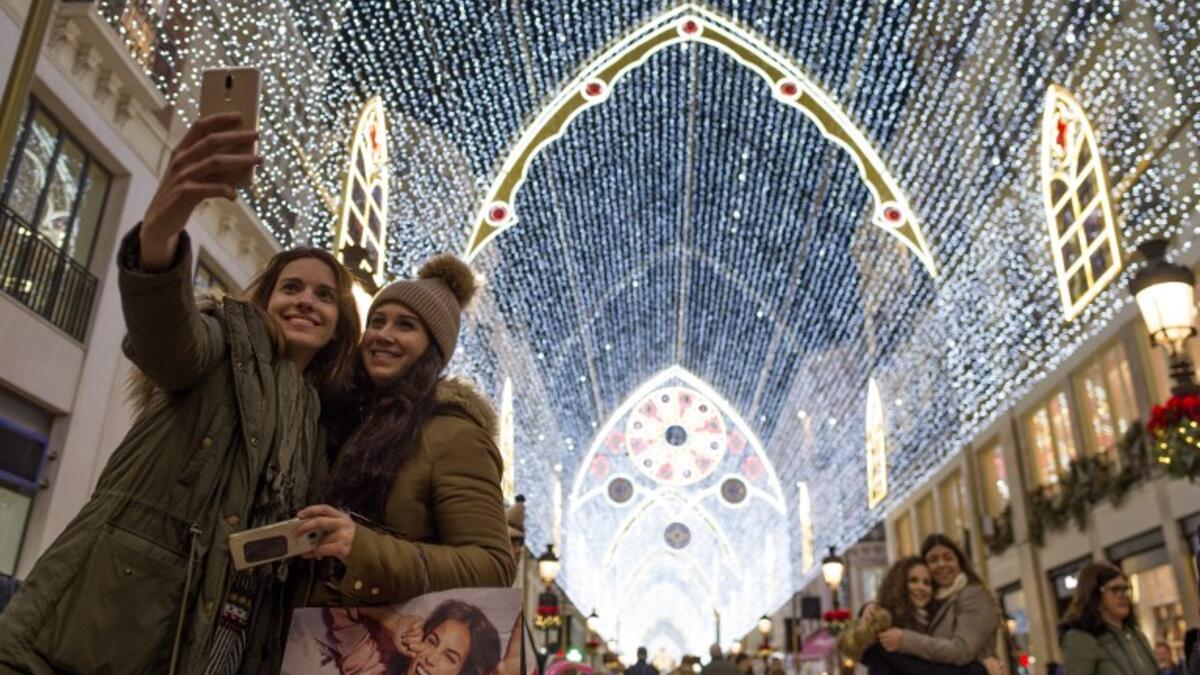 Two women take a selfie photo at Larios street, adorned with Christmas lights, in Malaga on December 19, 2018. 
JORGE GUERRERO / AFP