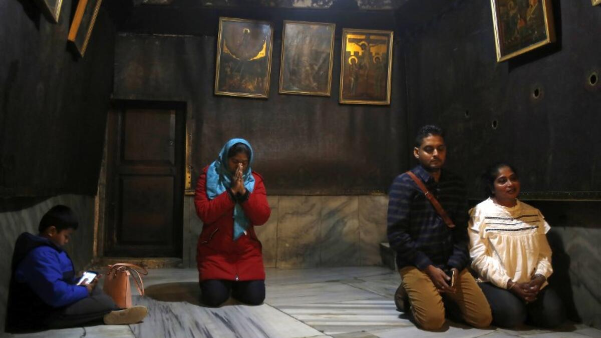 Christian worshipers pray inside the Grotto, believed to be the exact spot where Jesus Christ was born, at the Church of the Nativity in the biblical West Bank city of Bethlehem, on December 22, 2018, three days ahead of the Christmas celebration.  Musa Al Shaer/AFP