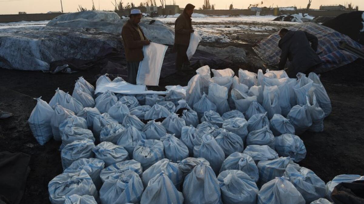 In this photograph 2019, Afghan workers fill sacks with coal at a coal yard amid heavy smog conditions in the outskirts of Kabul. 
WAKIL KOHSAR / AFP