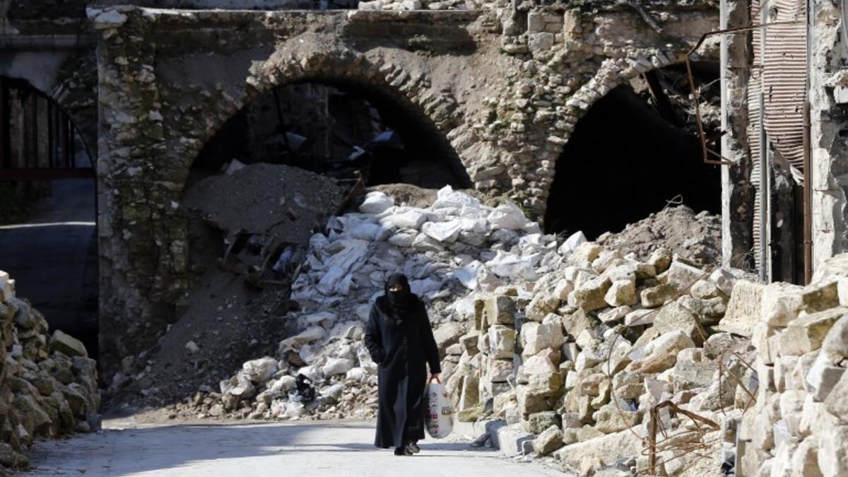 A general view shows a woman walking past debris in the old quarter of Syria's second city of Aleppo 
LOUAI BESHARA / AFP