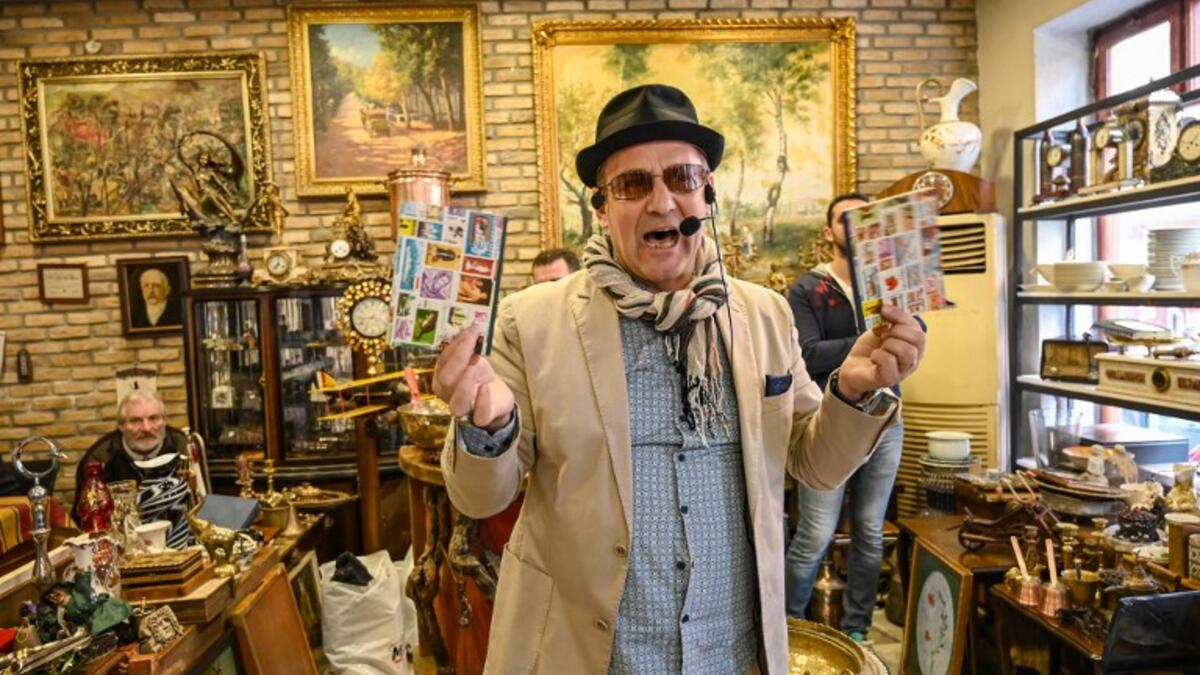 Auctioneer Ali Tuna shows items to the audience at an auction house in Istanbul's Balat.
OZAN KOSE / AFP