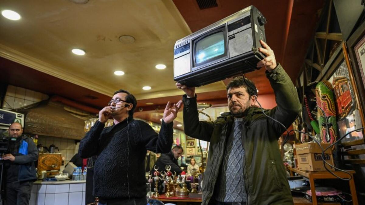 An auctioneer shows items to the audience at an auction house in Istanbul's Balat district. 
OZAN KOSE / AFP