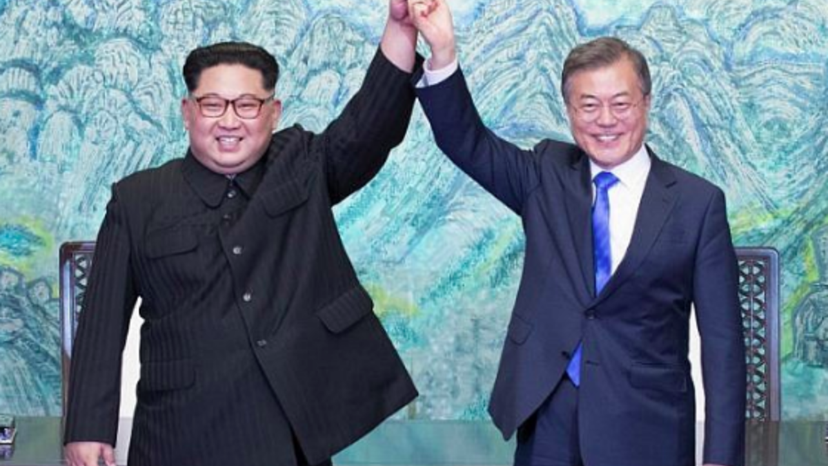 Kim Jong Un (L) and South Korea's President Moon Jae-in (R) raise their jointed hands during a signing ceremony near the end of their historic summit on April 27, 2018. Korea Summit Press Pool / AFP
