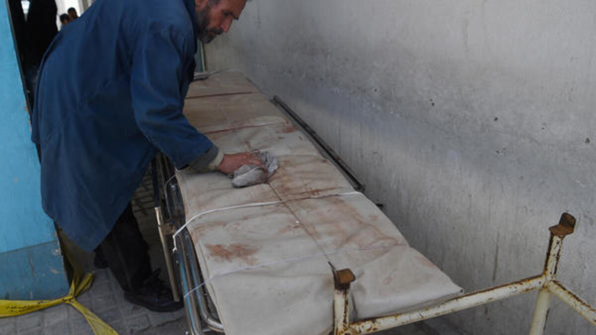 An Afghan medical staff member cleans a stretcher following a suicide bombing attack in Kabul on April 22, 2018. (AFP Photo/ Wakil Kohsar)