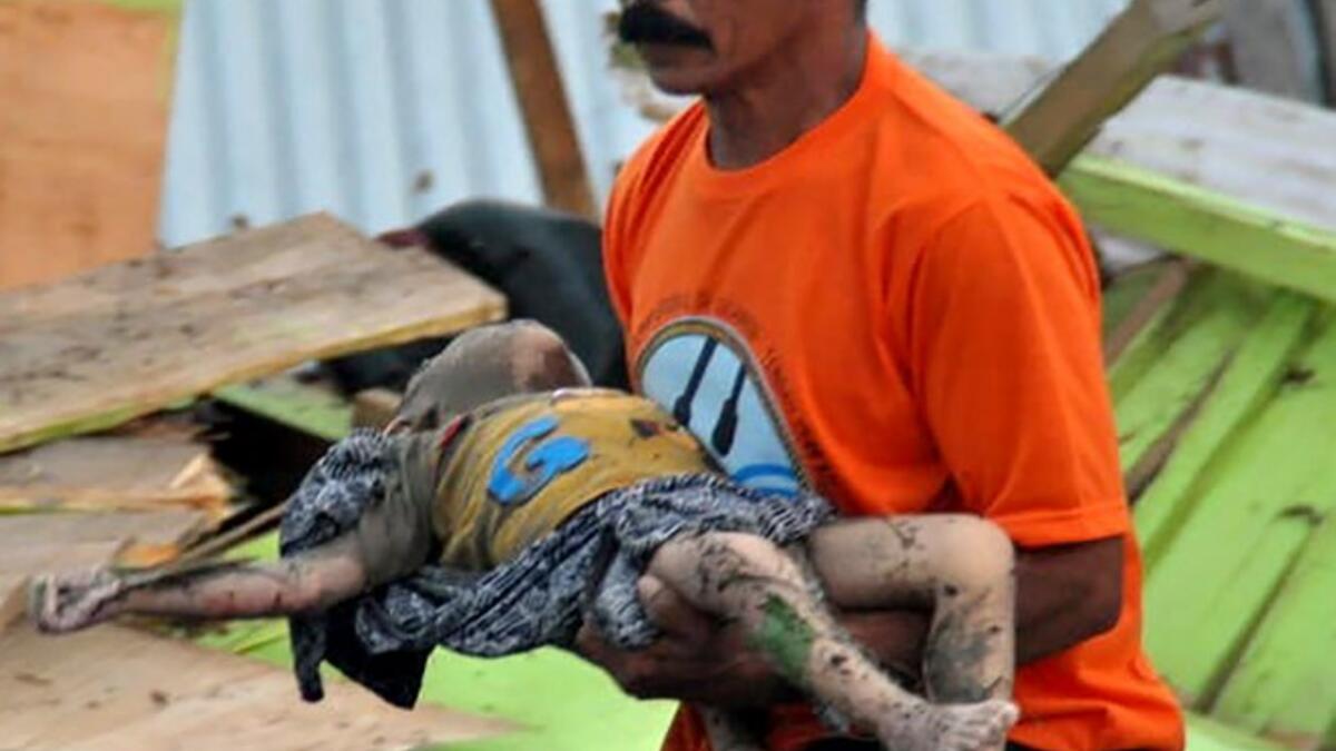 A man carries the body of a child after an earthquake and tsunami hit Palu, on Sulawesi island on September 29, 2018. (MUHAMMAD RIFKI / AFP)