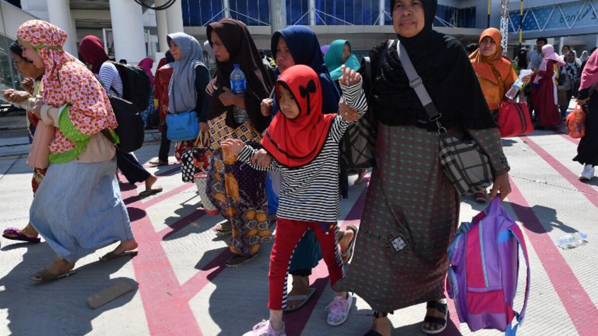 People gather on the apron as they wait to be evacuated by military aircraft at the quake-damaged Mutiara Sis Al Jufri airport in Palu, Indonesia's Central Sulawesi on September 30, 2018. (ADEK BERRY / AFP)