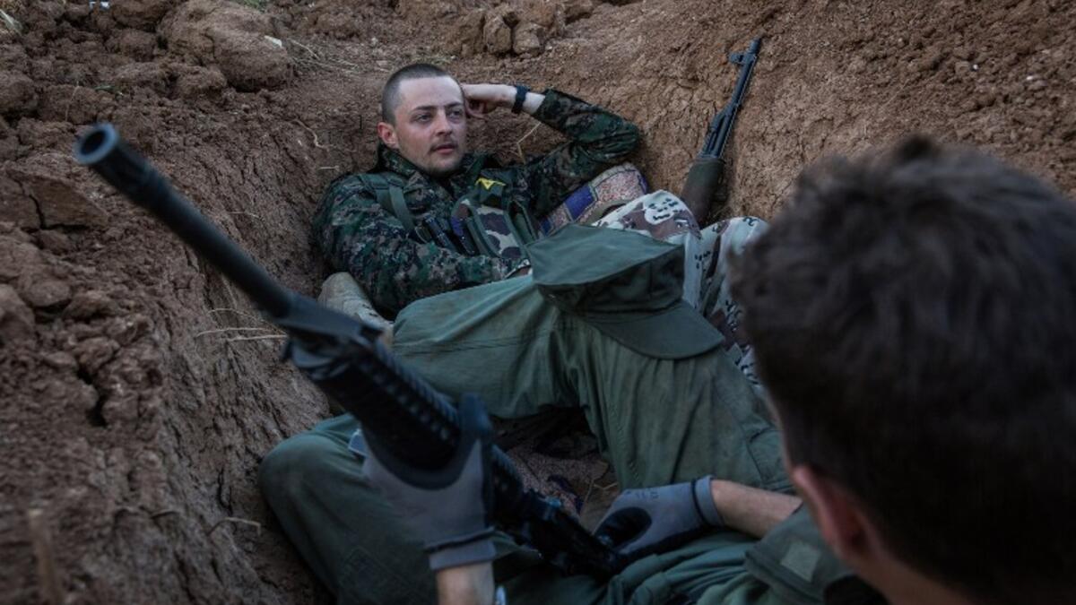 A 21-year-old Briton and a 23-year-old American nicknamed 'Hewal Sores' and 'Hewal Agir' stand guard at a post outside Tal Tamr on April 19, 2015. Working alongside YPG troops who speak little English, foreign fighters are often placed together in troops.