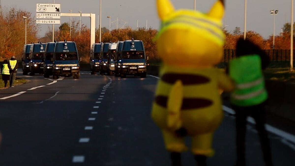 People and a mascot of Pikachu stand in front of gendarme's trucks on Caen's circular road on November 18, 2018 in Caen, northwestern France.
CHARLY TRIBALLEAU / AFP