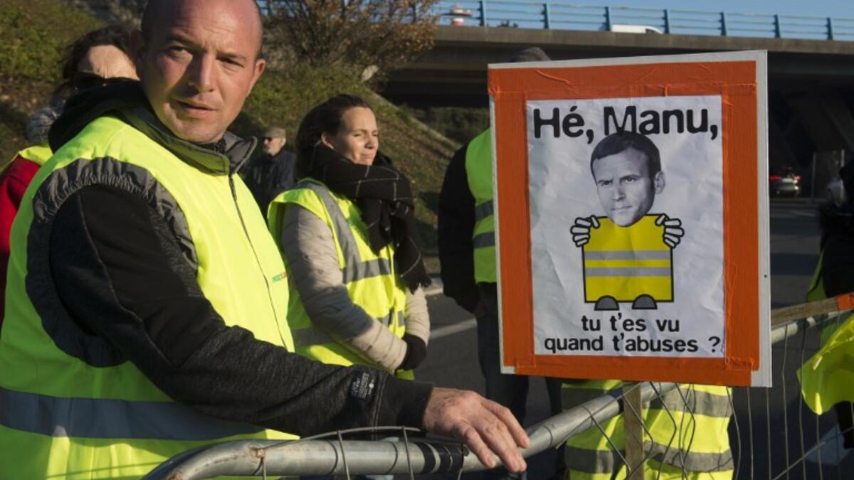 Protestors stand near a picture representing French President Emmanuel Macron while they slow down traffic on a road in Saint-Herblain, near Nantes, western France, on November 18, 2018.
SEBASTIEN SALOM GOMIS / AFP
