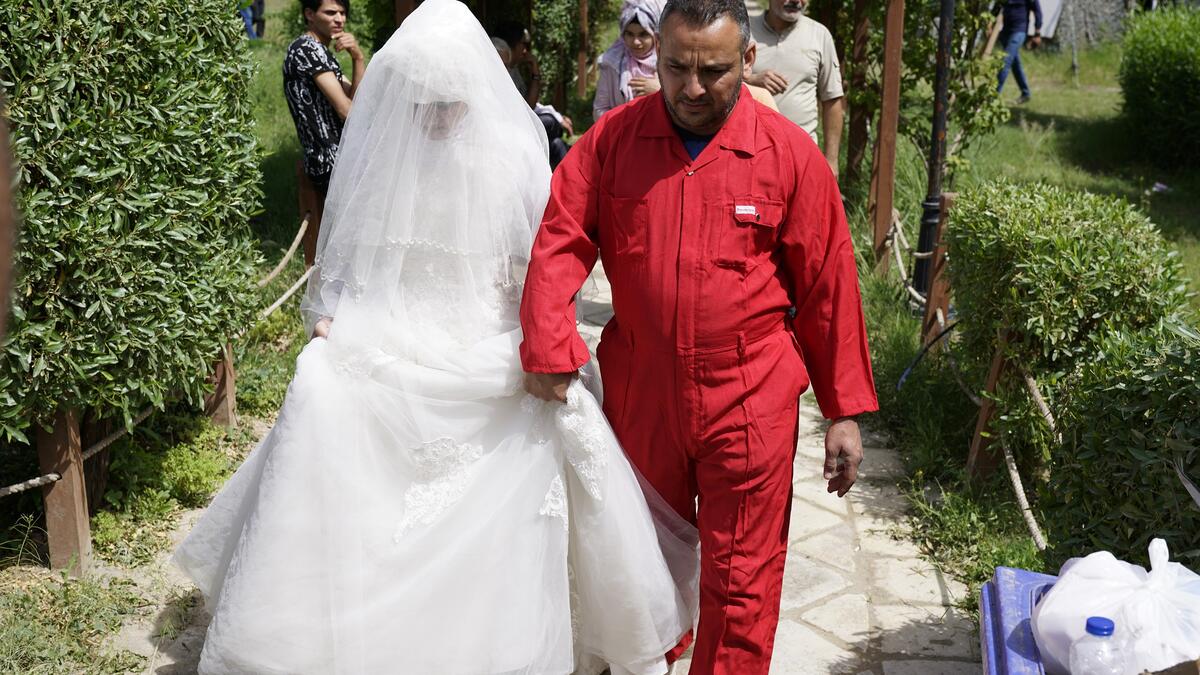 A man in prison suit in chains, next to him there is a huge gift-wrapped box, which was a woman in a wedding dress. 
Baghdad's Woman Association