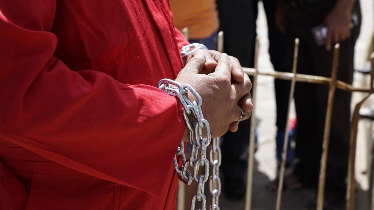 A man in an orange prison jumpsuit in chains protest Iraq's raping law. 
Baghdad's Woman Association
