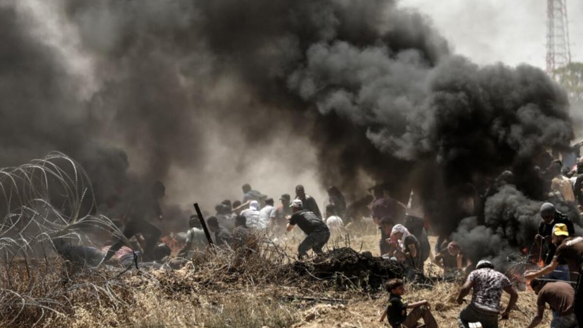 Palestinians clash with with Israeli forces near the border between the Gaza strip and Israel east of Gaza City on May 14, 2018, as Palestinians protest over the inauguration of the US embassy following its controversial move to Jerusalem. MAHMUD HAMS / AFP