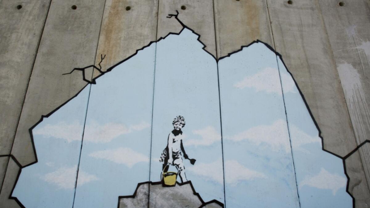A Palestinian boy play on the beach, drawn on the security barrier in Bethlehem /AFP
