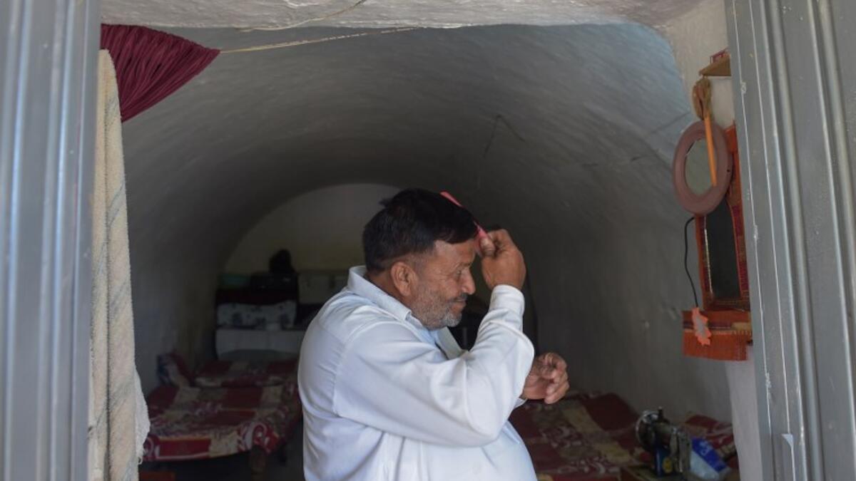 Pakistani villager Haji Abdul Rasheed combs his hair at the entrance to his cave room in Nikko village. 
AAMIR QURESHI / AFP