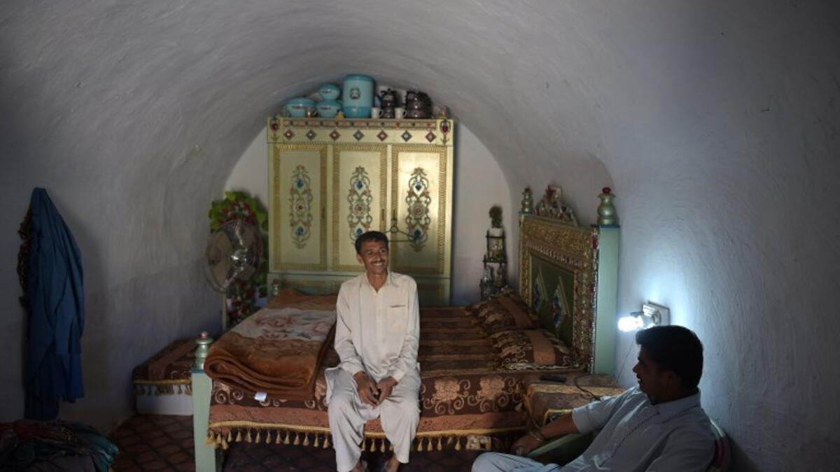 Pakistani villager Ameer Ullah Khan (L) chats with a friend in his cave room in Nikko village.
AAMIR QURESHI / AFP