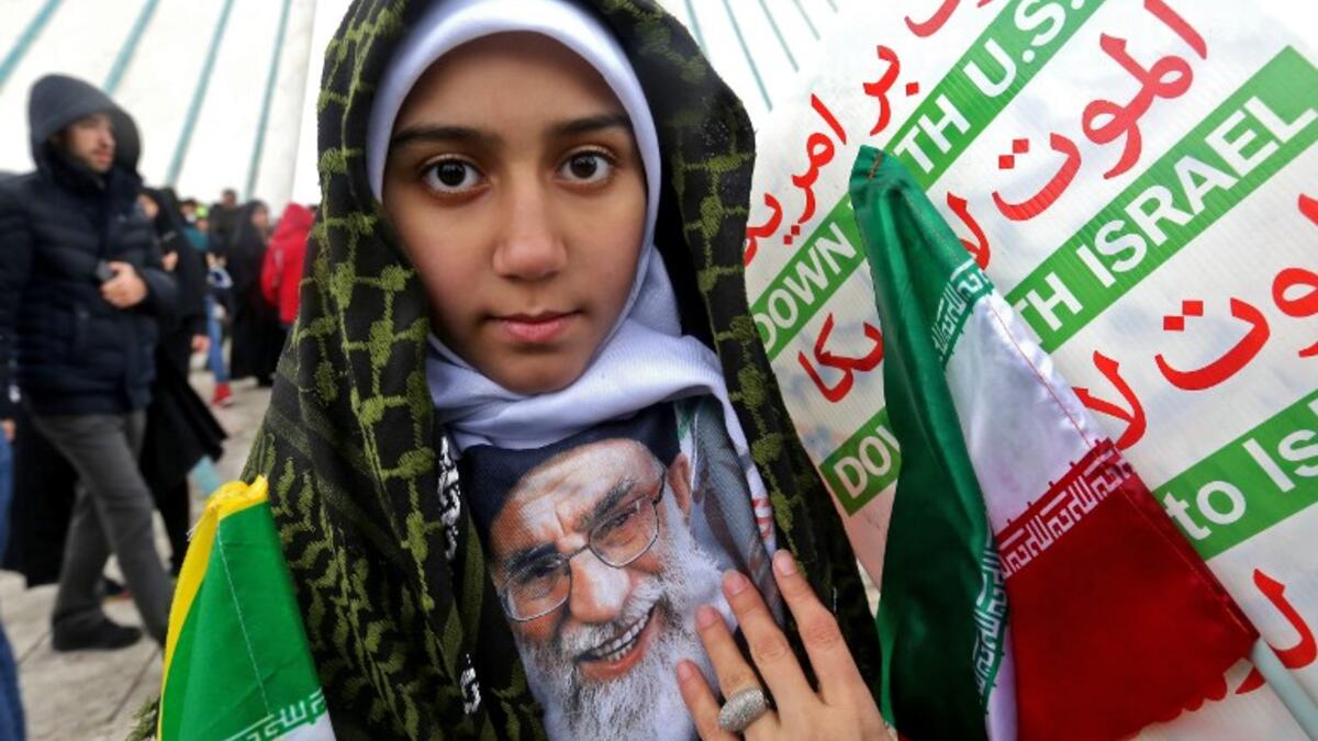 An Iranian girl poses with a potrait of the country's Supreme Leader Ali Khamenei with signs reading "Down with USA" and "Down with Israel" during a ceremony celebrating the 40th anniversary of Islamic Revolution.
ATTA KENARE / AFP