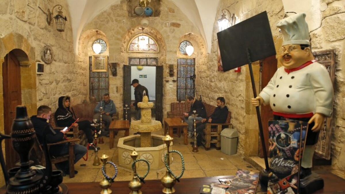 Men smoke waterpipes (shisha or hookah) as they sit at the premises of the first traditional Turkish bath (Hammam) opening in the occupied Palestinian West Bank city of Hebron on March 11, 2019. 
HAZEM BADER / AFP