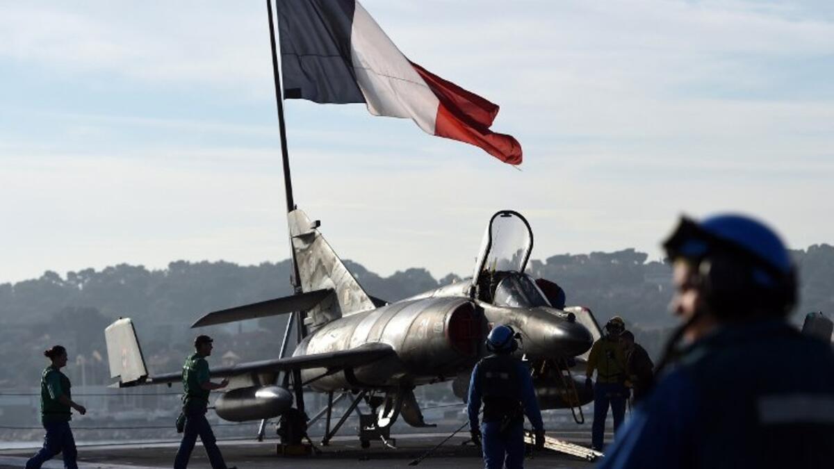 A French flag flies above French naval technicians working on the flight deck of the aircraft (AFP)