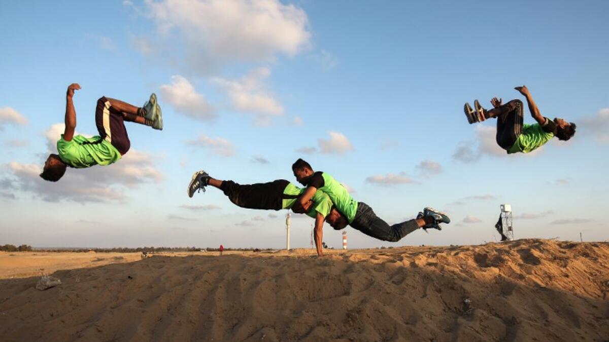 In the same tent site, east of Rafah in the southern Gaza Strip, Palestinian youths practice their parkour skills. Photo taken on April 10, 2018. SAID KHATIB / AFP