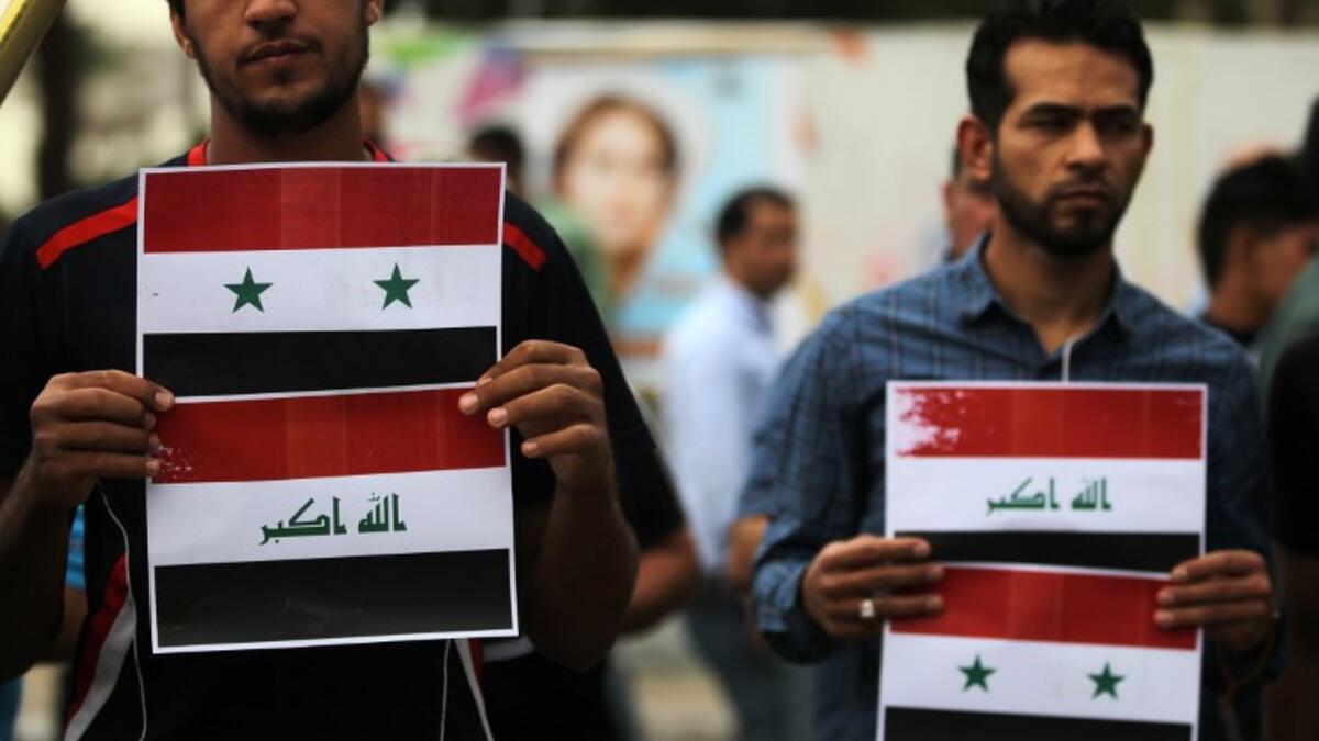 Two protestors display Syrian and Iraqi flags down Baghdad’s Tahir Region on April 15, 2017, AHMAD AL-RUBAYE / AFP
