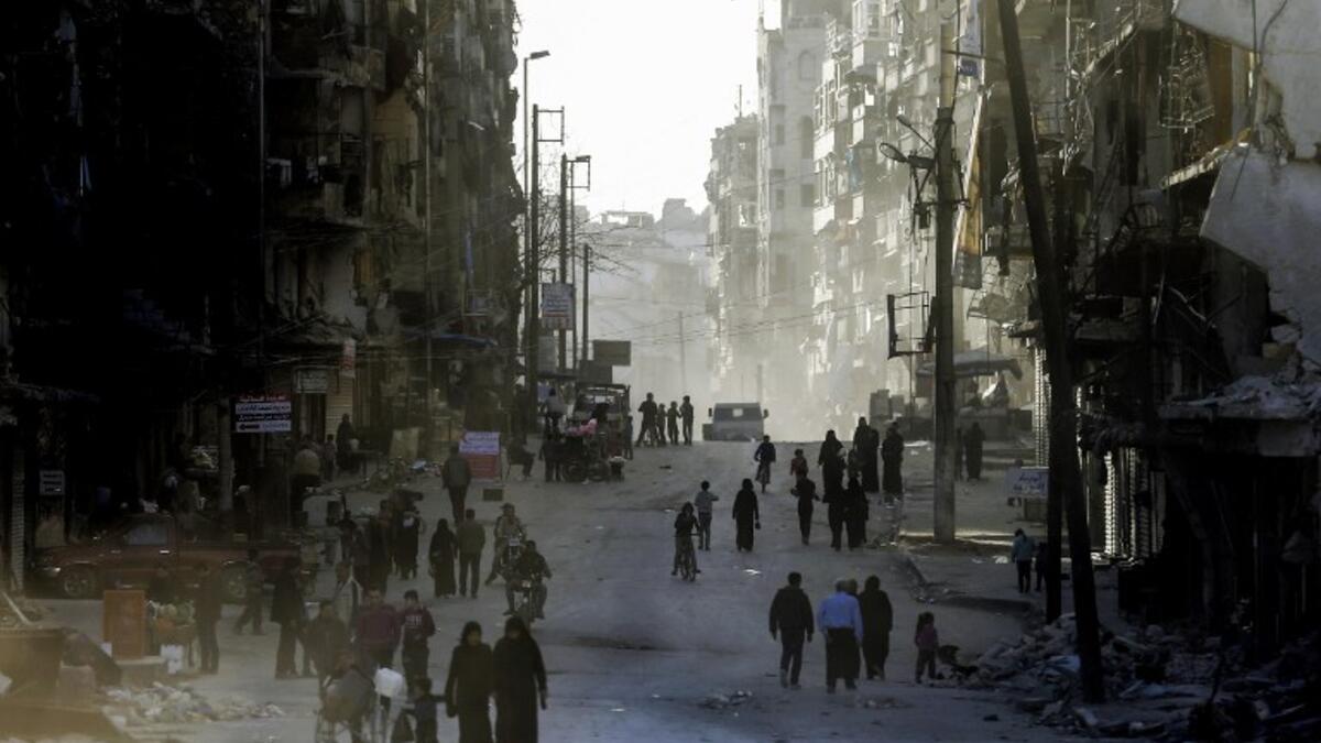Syrians walk the streets of the formerly rebel-held neighborhood of al-Shaar in Aleppo, which was recaptured by government forces in December 2016.