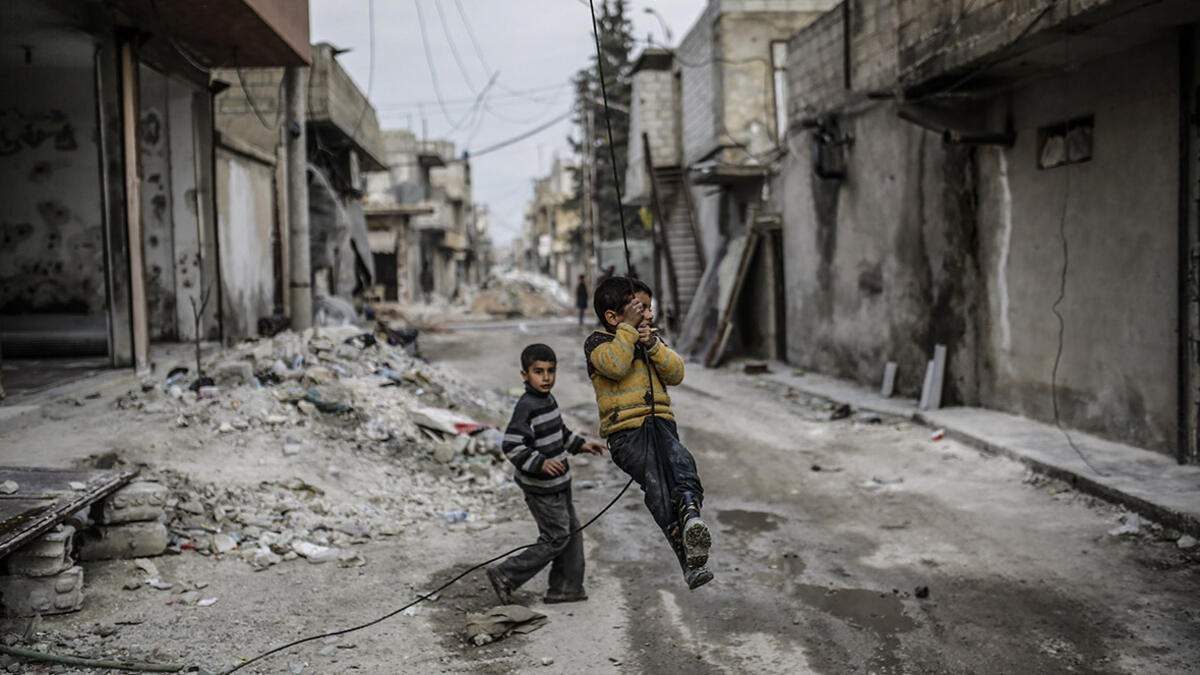 Children swing on an electrical wire hanging off a damaged building in Kobani. After the liberalization from Daesh in 2015, many people have returned to the city. Yet, reconstruction has been made difficult by the closure of border crossings with Turkey that prevented the importation of goods such as cement, iron, medicines, food and technology.