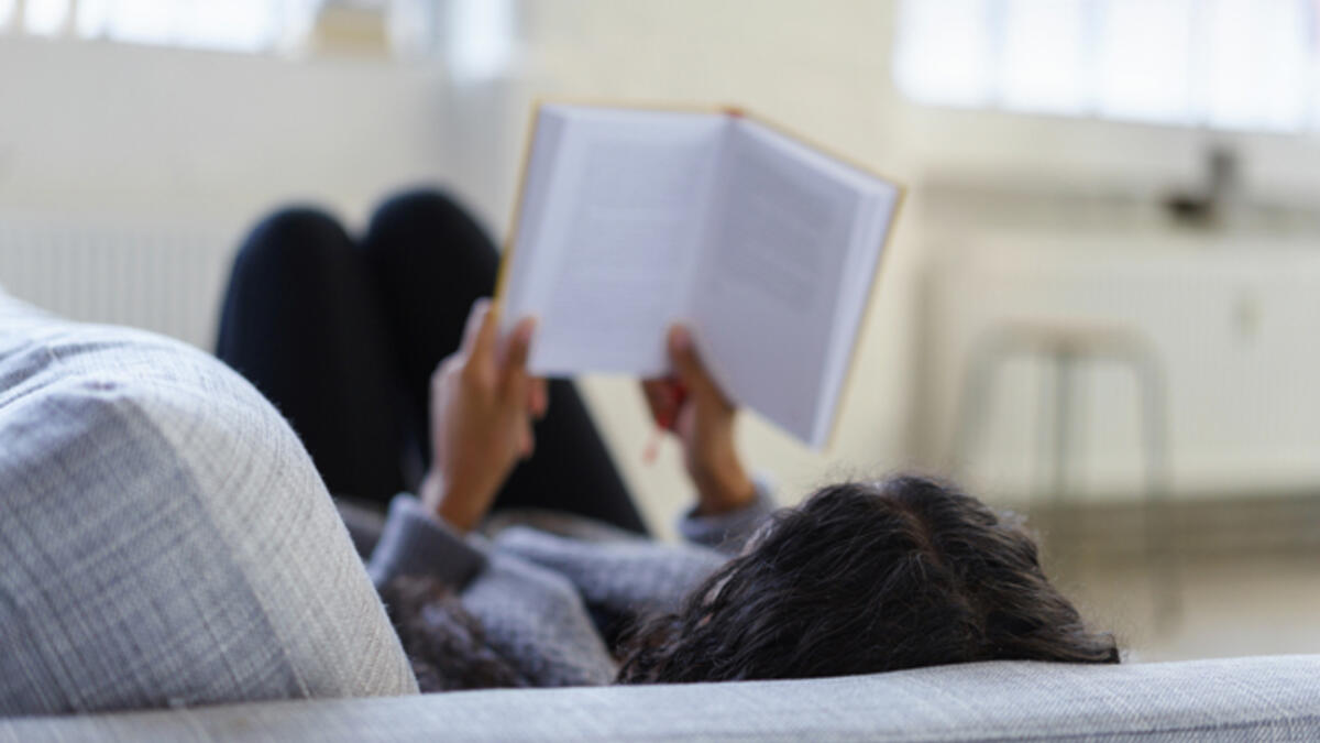 woman reading book couch
