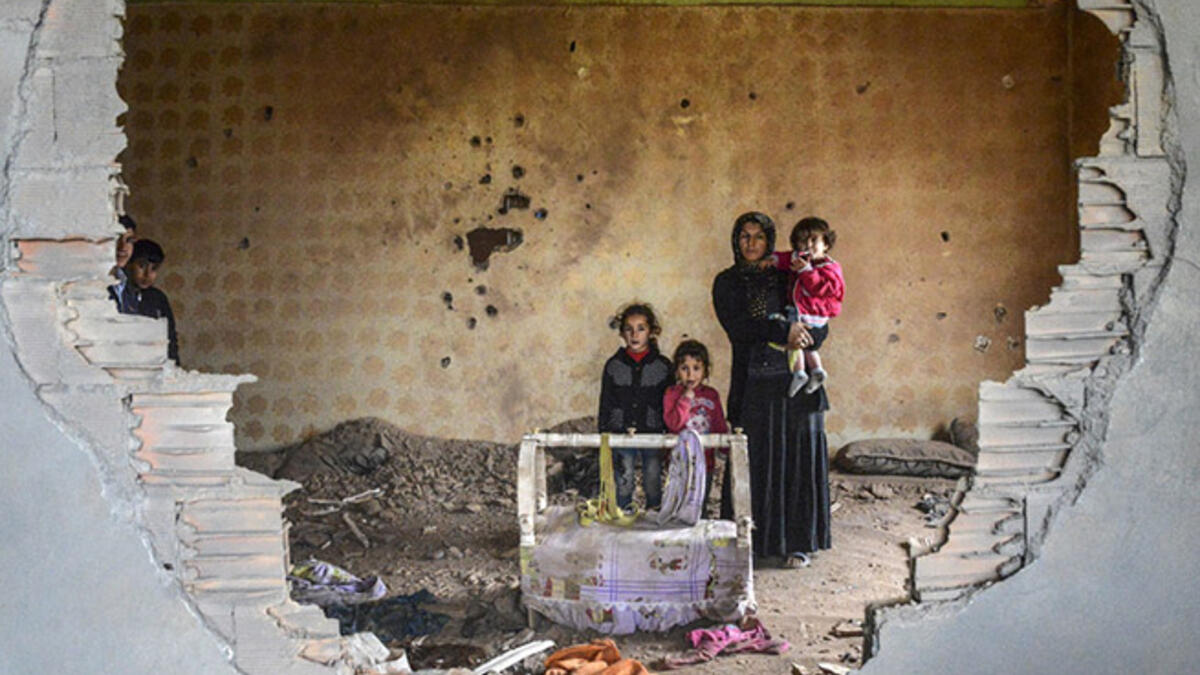 Turkey’s descent into war: A woman and her children stand in the ruins of battle-damaged house in the Kurdish town of Silopi, in southeastern Turkey, near the border with Iraq on January 19, 2016.
