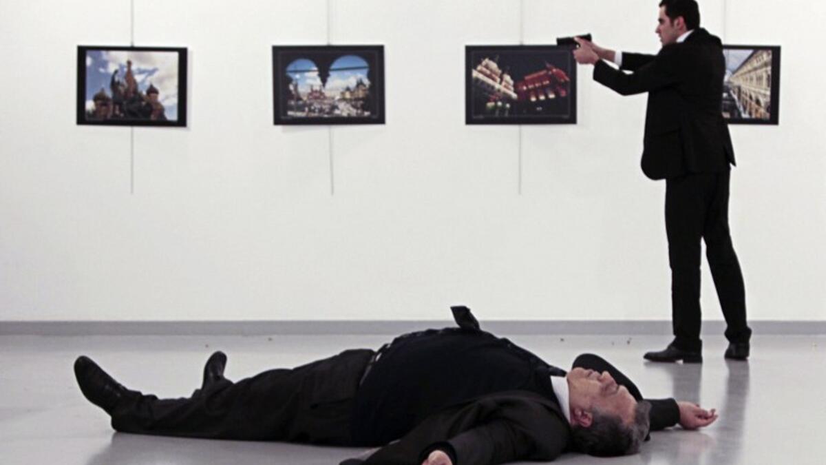 This picture taken on December 19, 2016 shows Andrei Karlov, the Russian ambassador to Ankara, lying on the floor after being shot by Mevlut Altintas (R) during an attack at a public event in Ankara.