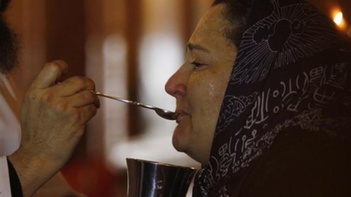 A coptic priest gives a mourning Egyptian woman her communion during Sunday mass on at the Al-Qiddissine church.