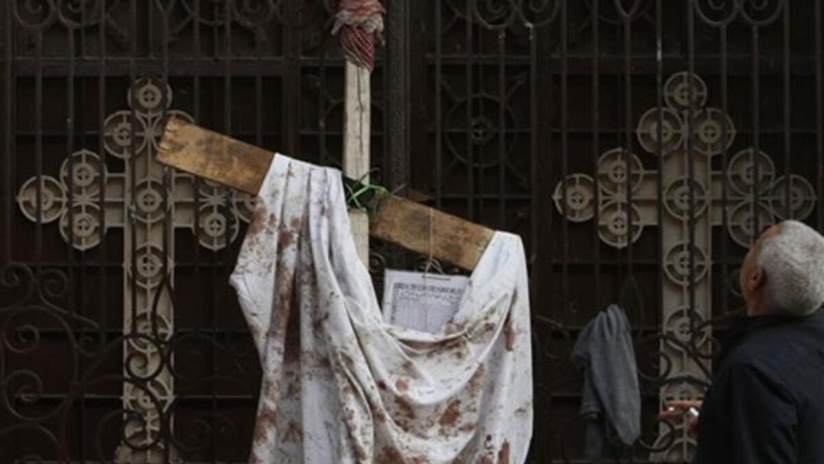 An Egyptian man stands next to a blood-stained peace of cloth hung outside the Al-Qiddisine church in the Mediterranean port city of Alexandria.