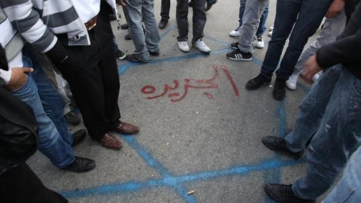 Palestinian protesters step on a Star of David sprayed on the ground with the name of the Al-Jazeera written in red Arabic letters in the middle during a demonstration in the West Bank city of Ramallah.