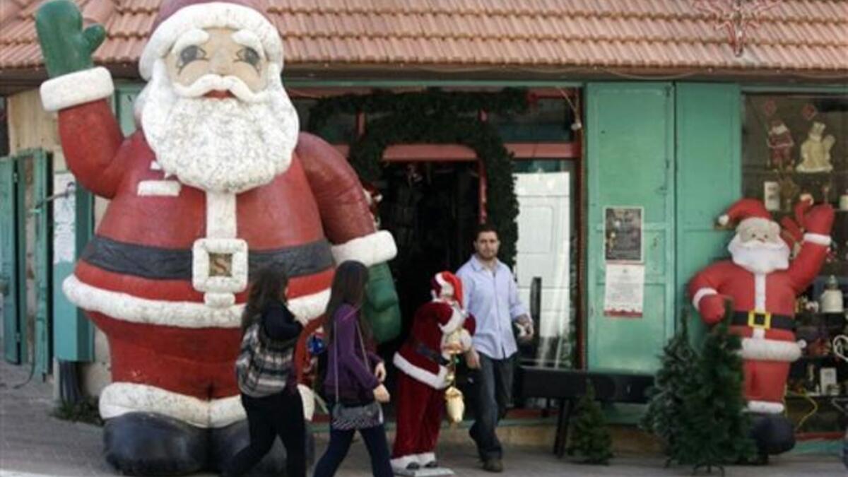 Palestinian women walk past a giant Santa Claus in the biblical West Bank town of Bethlehem, as the town prepares for scores of Christian pilgrims gathering in the traditional birthplace of Jesus Christ to celebrate Christmas.