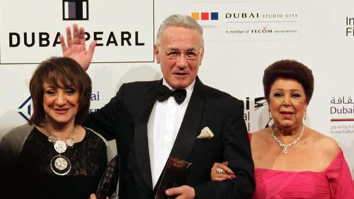 Egyptian actor Izzat Abul Awf poses for a picture with fellow actress and former model Ragaa al-Giddawi (R) and an unidentified guest during the closing ceremony of the Seventh Dubai International Film Festival (DIFF) in the Gulf Emirate.