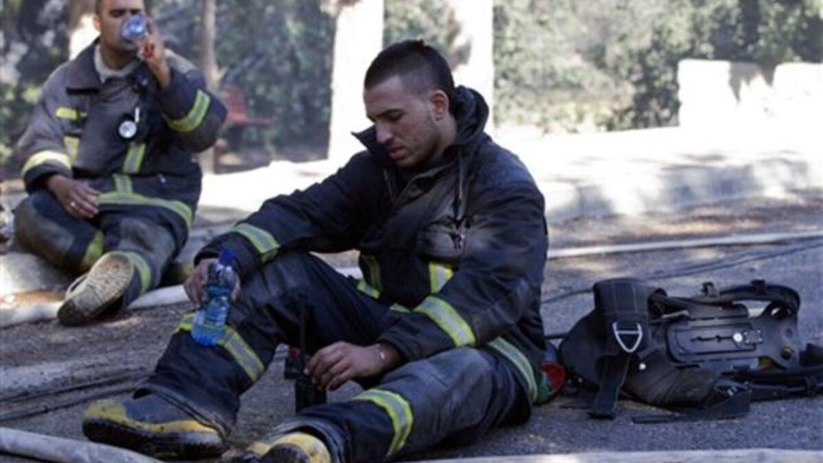 Israeli firefighters take a break after dousing flames in the village of Ein Hod.