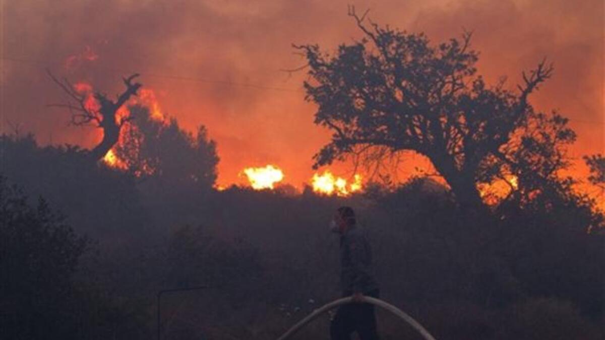 Israeli firefighters work on the slope of a burning hill in Tirat Ha Carmel near the northern city of Haifa